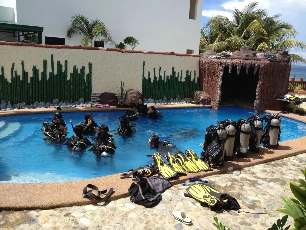 Des personnes en équipement de plongée s'entrainent dans une piscine.