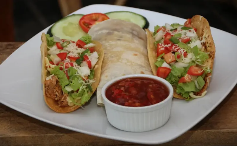 Assiette de tacos garnis de légumes et de sauce.