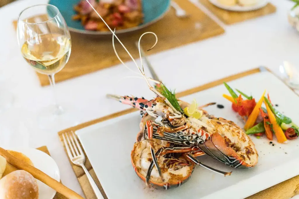 Une table est dressée avec un plat de homard et un verre de vin.