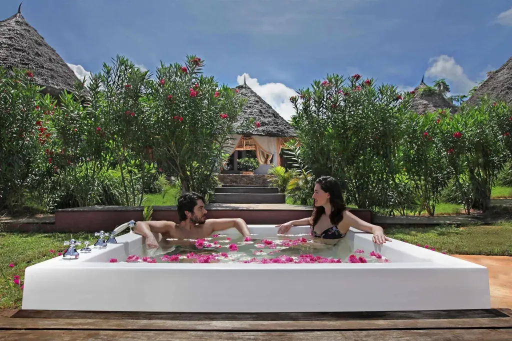 Un couple se détend dans un grand bain à remous extérieur décoré de fleurs.