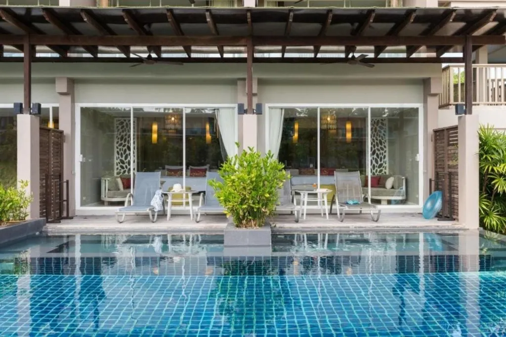 Terrasse avec transats et piscine devant de grandes baies vitrées.