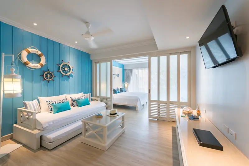 Espace de vie lumineux avec canapé blanc et chambre séparée par des cloisons ajourées.