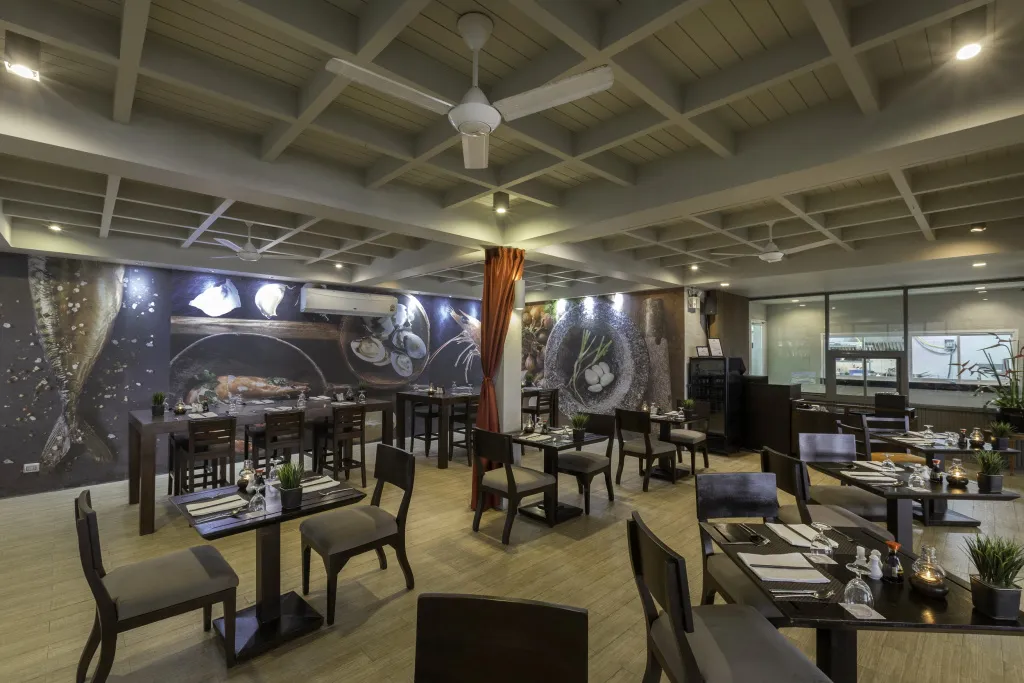Une salle lumineuse avec des tables dressées pour un repas.