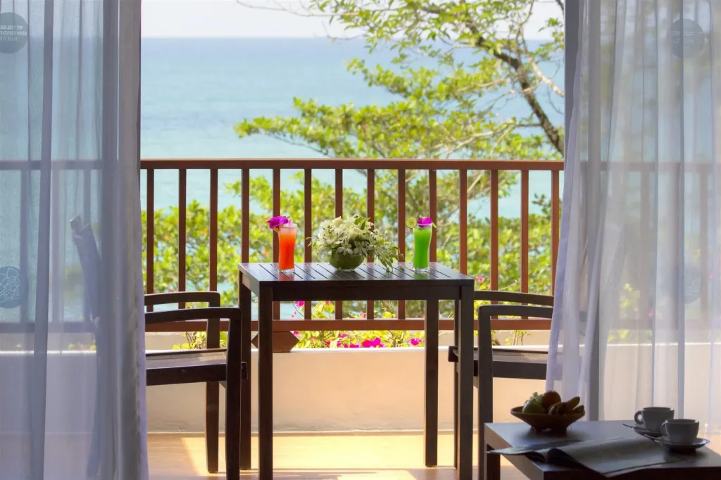 Une terrasse avec une table et des boissons offre une vue sur la mer.