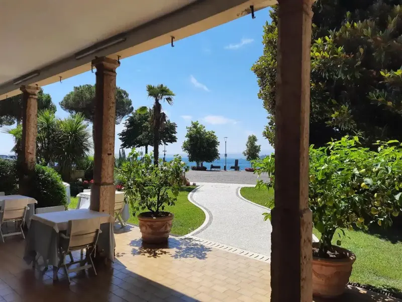 Terrasse ombragée donnant sur un jardin verdoyant et la mer.