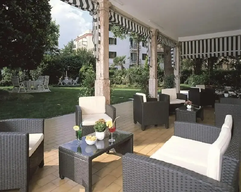 Espace de détente extérieur avec mobilier en rotin et végétation luxuriante.