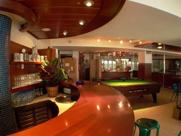 Un comptoir de bar en bois rouge s'étend en arc de cercle dans une salle éclairée.