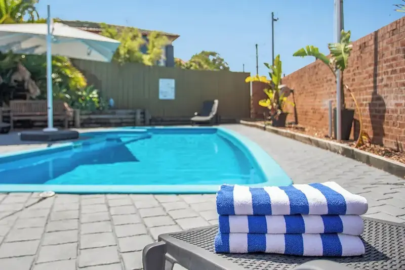 Une piscine rectangulaire entourée d'une terrasse pavée et de végétation luxuriante.