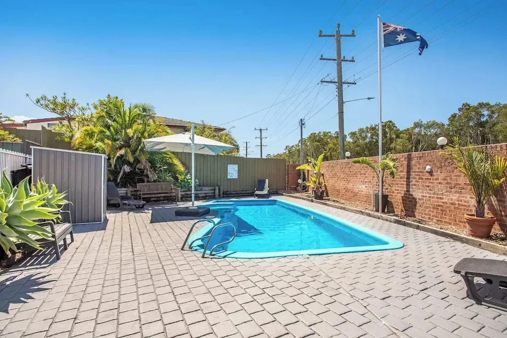 Une piscine rectangulaire entourée d'une terrasse pavée et de végétation luxuriante.