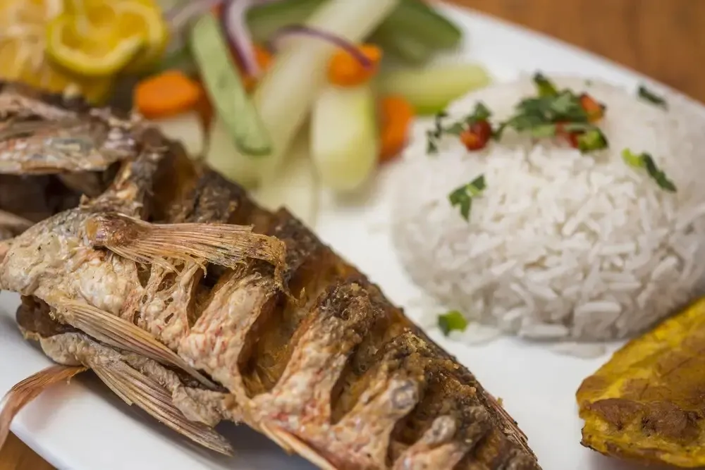 Assiette de poisson frit servi avec du riz et des légumes.