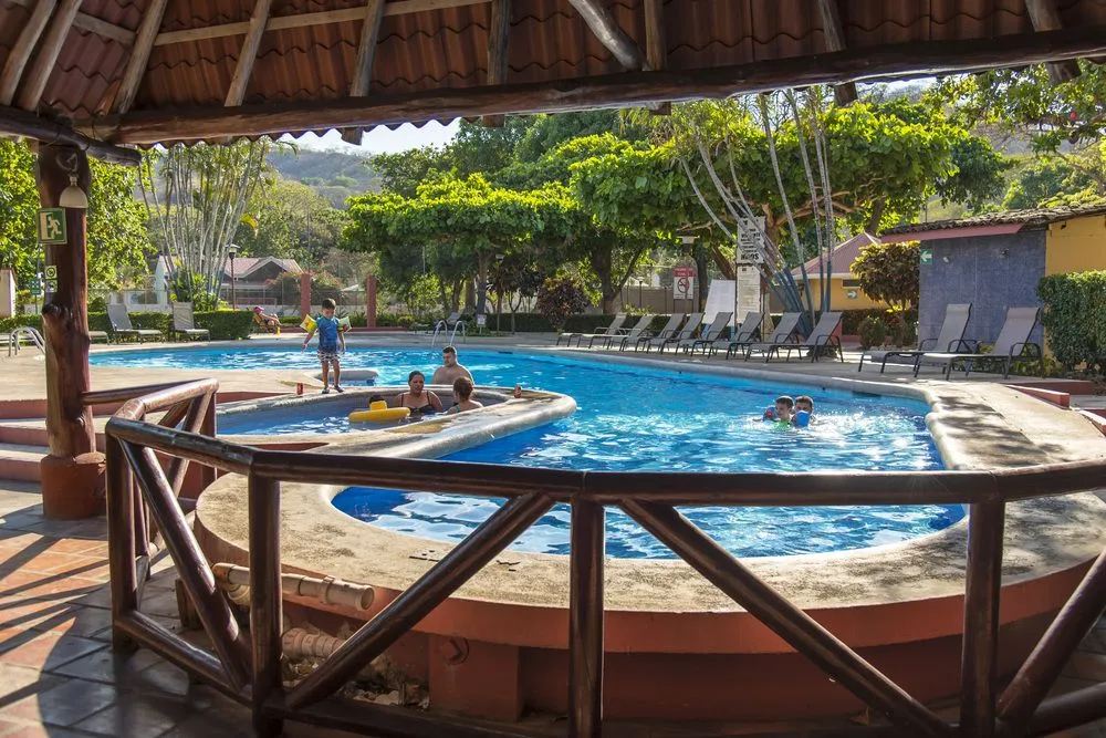 Une piscine avec des personnes se baignant et des transats à proximité.