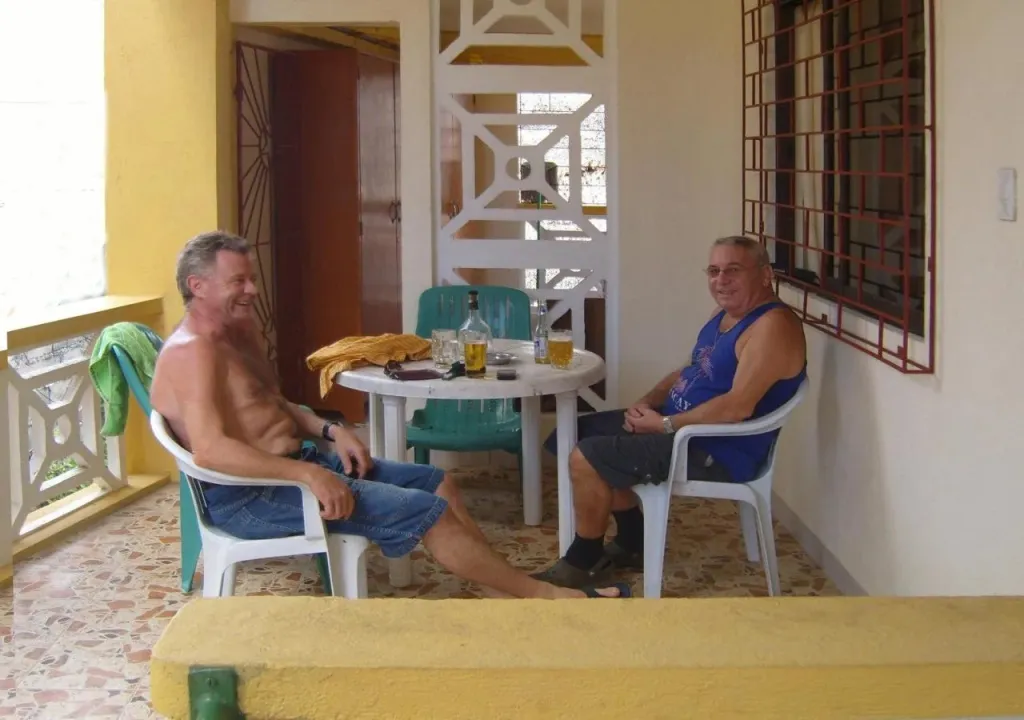 Deux hommes sont assis à une table sur une terrasse.