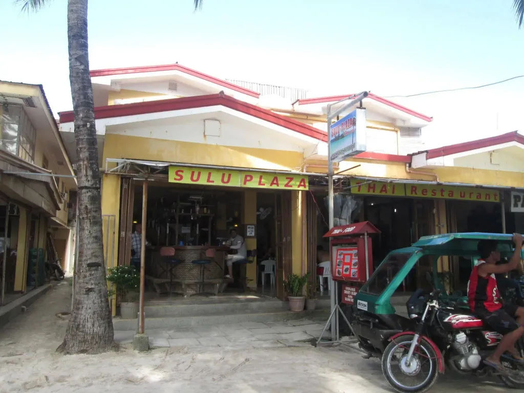 Façade d'un bâtiment avec une devanture de restaurant et un scooter garé.