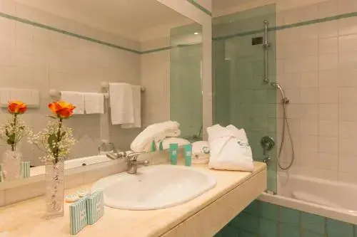 Une salle de bain lumineuse avec lavabo, miroir et douche.