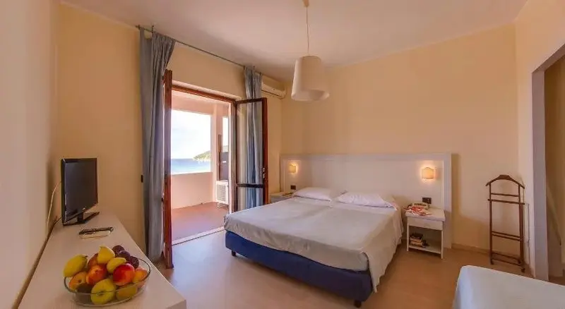 Une chambre lumineuse s'ouvre sur un balcon avec vue sur la mer.