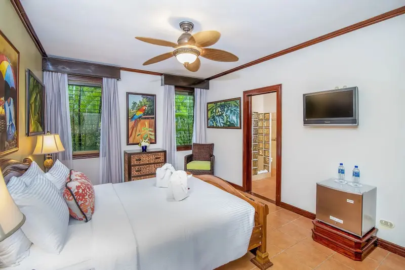 Une chambre lumineuse avec un grand lit et une décoration tropicale.