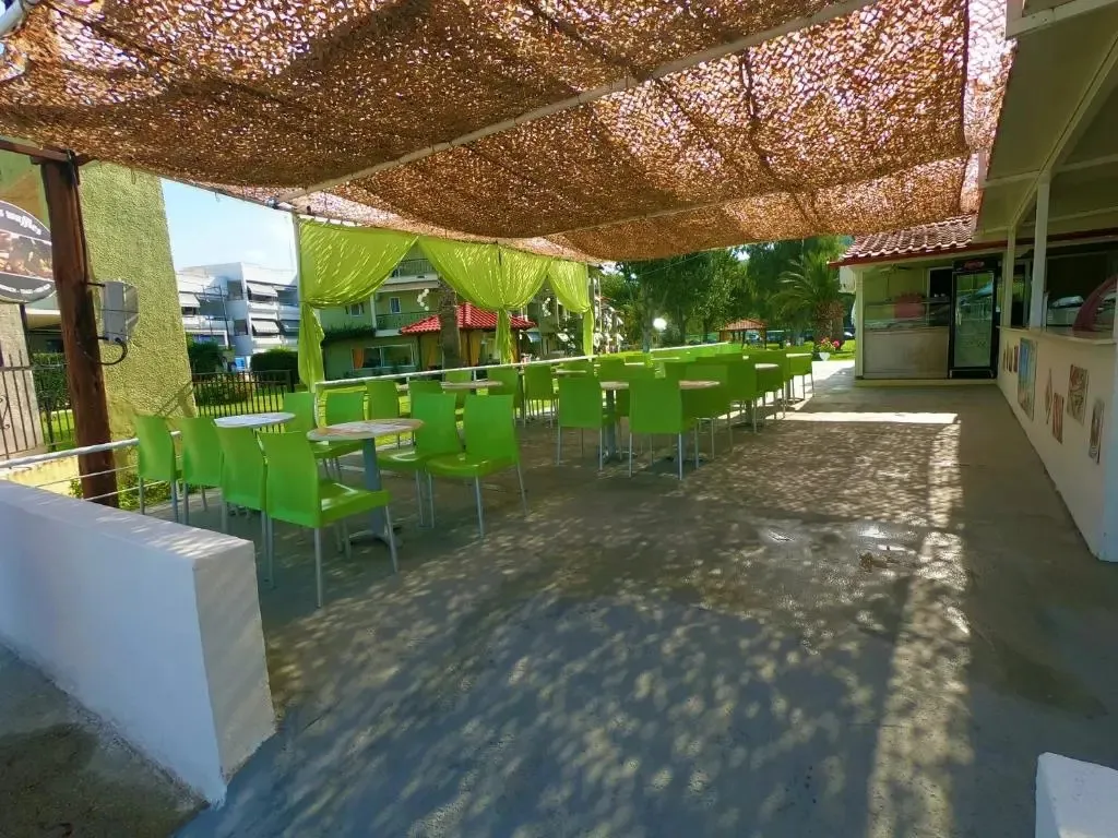 Terrasse ombragée avec tables et chaises vertes.