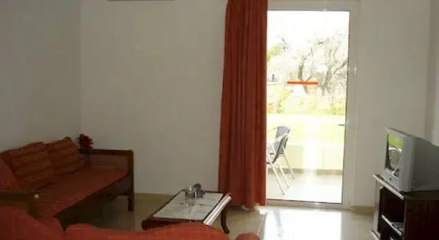 Un espace de séjour lumineux avec un canapé et une télévision, donnant sur une terrasse.