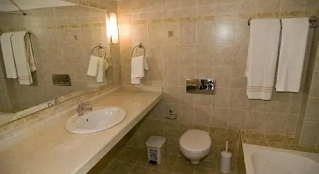 Une salle de bain claire avec lavabo, toilette et serviettes.