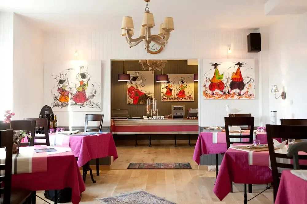Une salle lumineuse avec des tables dressées et des tableaux colorés.
