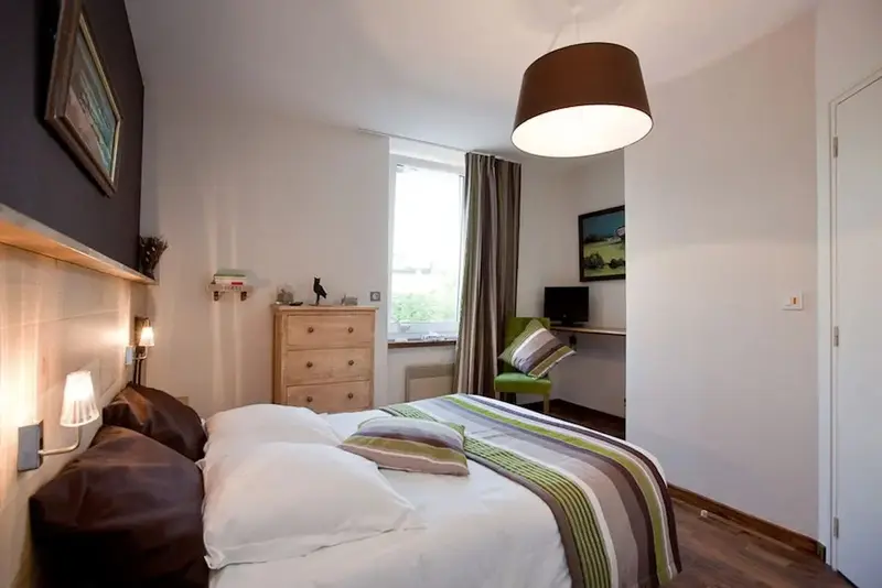 Une chambre lumineuse avec un lit fait et une commode en bois.