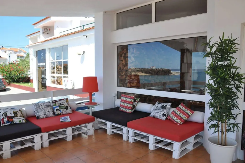 Espace de détente extérieur avec assises basses et vue sur la mer.
