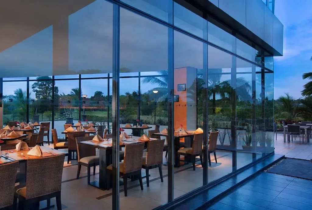Une salle de restaurant lumineuse avec de grandes baies vitrées donnant sur un paysage verdoyant.