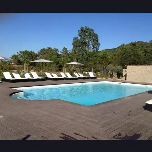 Une piscine rectangulaire entourée d'une terrasse en bois avec des transats blancs.