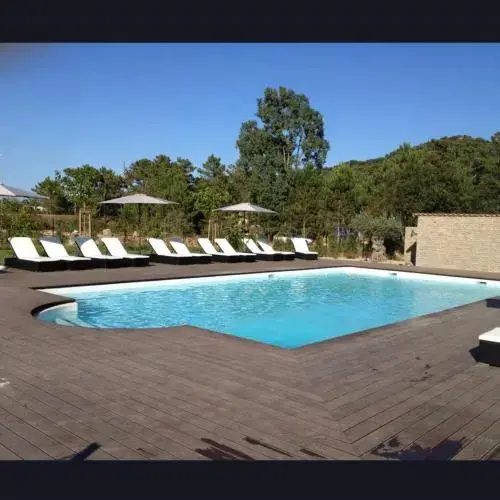 Une piscine rectangulaire entourée d'une terrasse en bois avec des transats blancs.