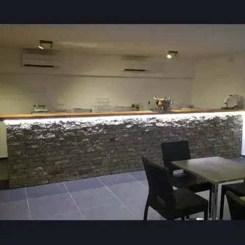 Un comptoir de bar en pierre face à des tables et des chaises.