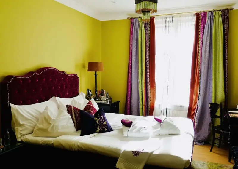 Une chambre lumineuse avec un grand lit recouvert de coussins et de couvertures.