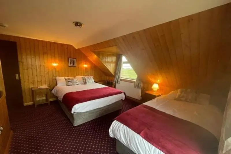 Une chambre aux murs lambrissés avec deux lits simples et une décoration chaleureuse.