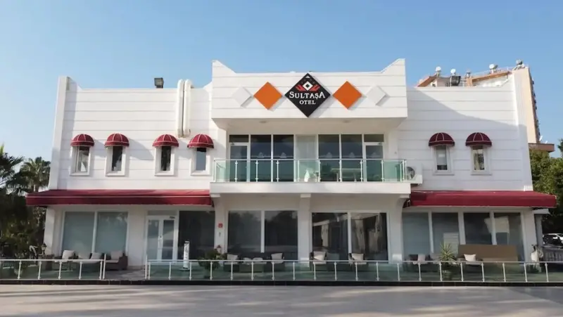 Façade d'un bâtiment blanc à deux étages avec des balcons et des auvents rouges.