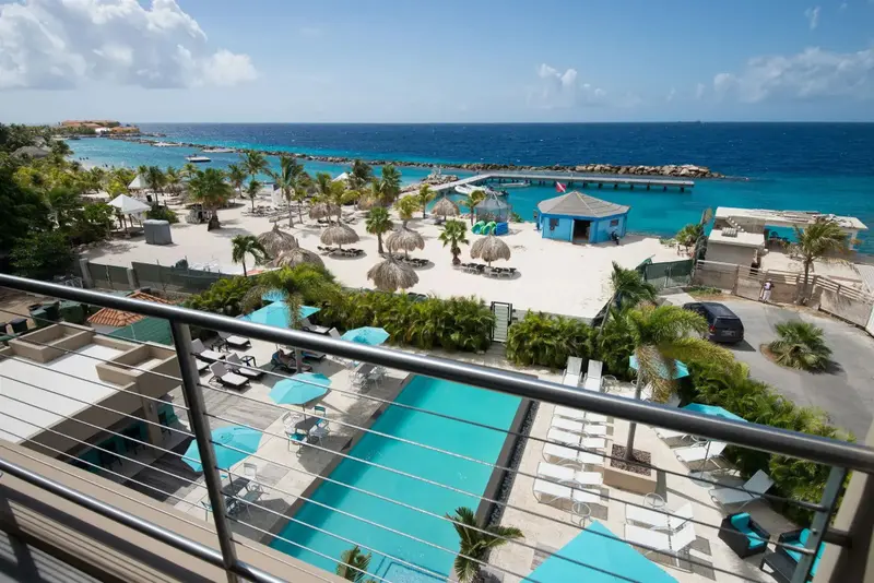 Vue aérienne sur une plage avec parasols et une piscine turquoise.