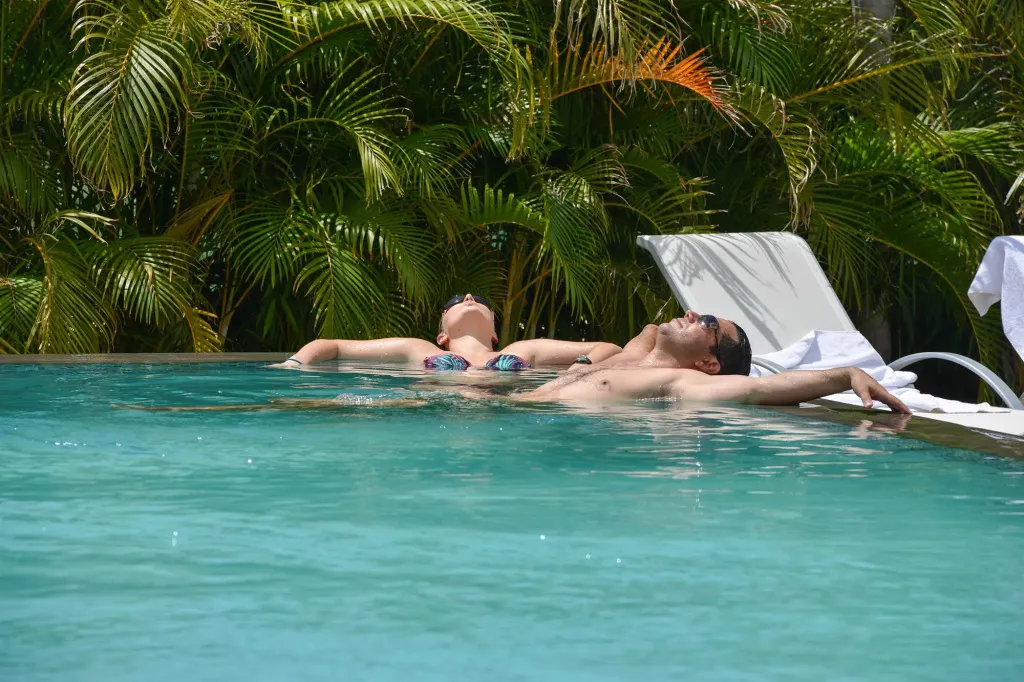 Deux personnes se relaxent sur des chaises longues dans une piscine.