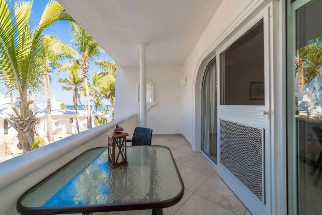 Une terrasse carrelée avec une table et une chaise offre une vue sur la mer et la végétation.