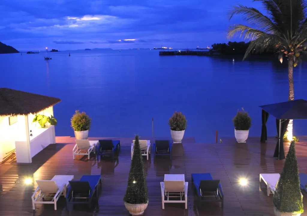 Terrasse lumineuse avec mobilier de détente face à la mer au crépuscule.