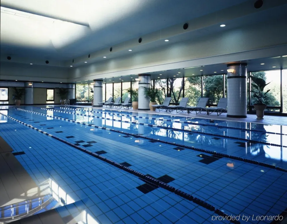 Une piscine interieure avec des transats alignes pres des fenetres.