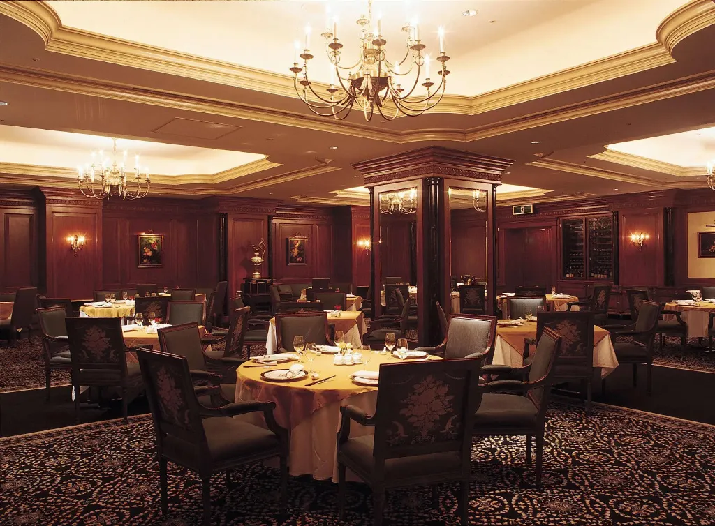 Une salle de restaurant élégante avec des tables dressées et un éclairage chaleureux.
