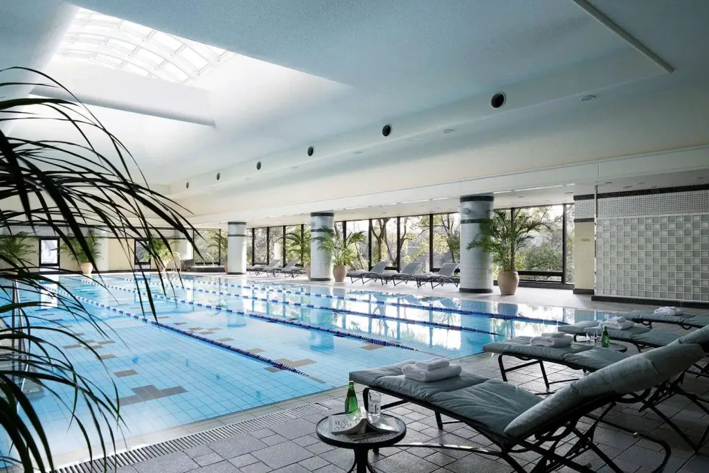 Une piscine intérieure lumineuse avec des transats alignés le long du bassin.