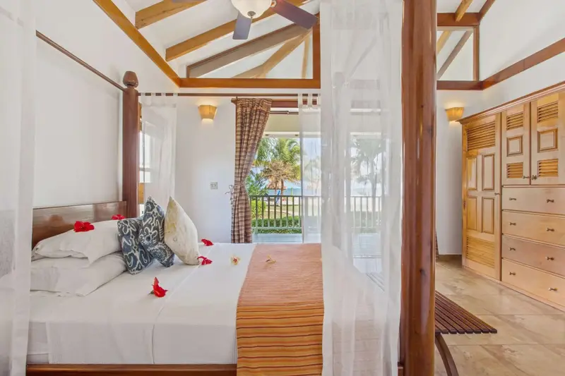 Une chambre lumineuse avec un lit à baldaquin donnant sur une vue tropicale.