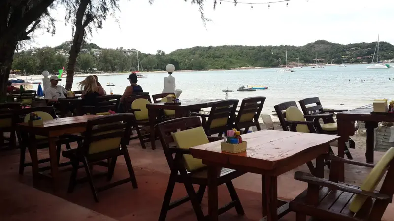 Tables et chaises disposées sur une terrasse en bord de mer.