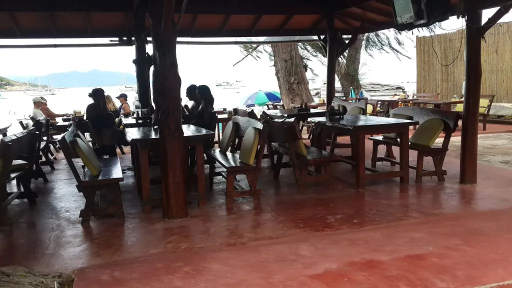 Tables et chaises disposées sous une structure abritée face à la mer.