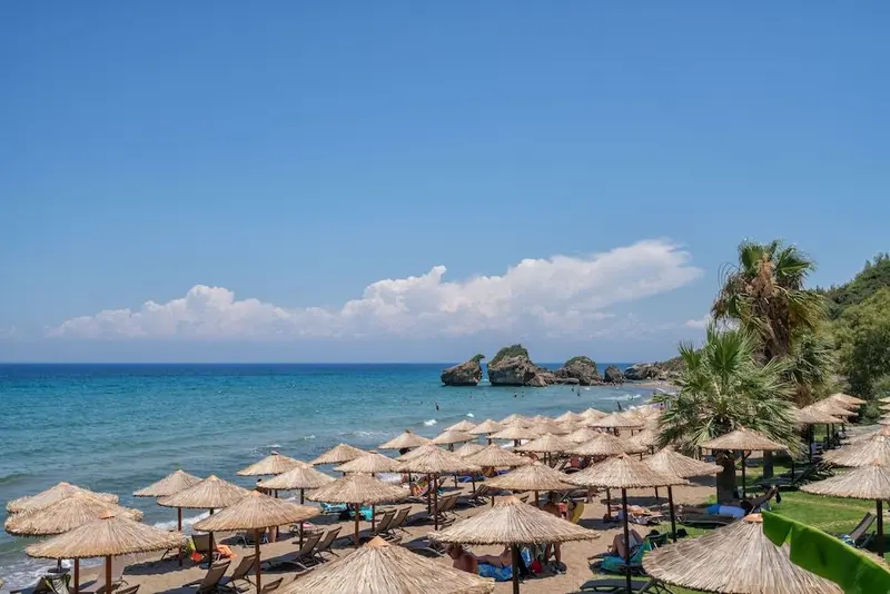 Une plage ensoleillée avec des parasols de paille et des transats.