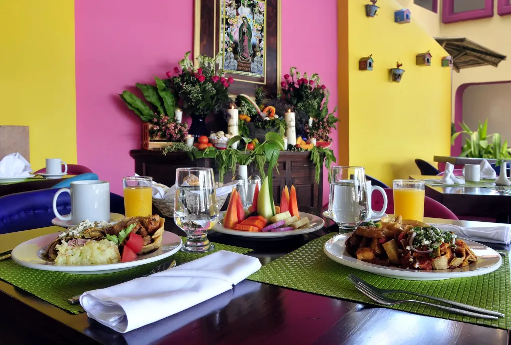 Une table est dressée avec des assiettes de nourriture, des verres et des couverts.