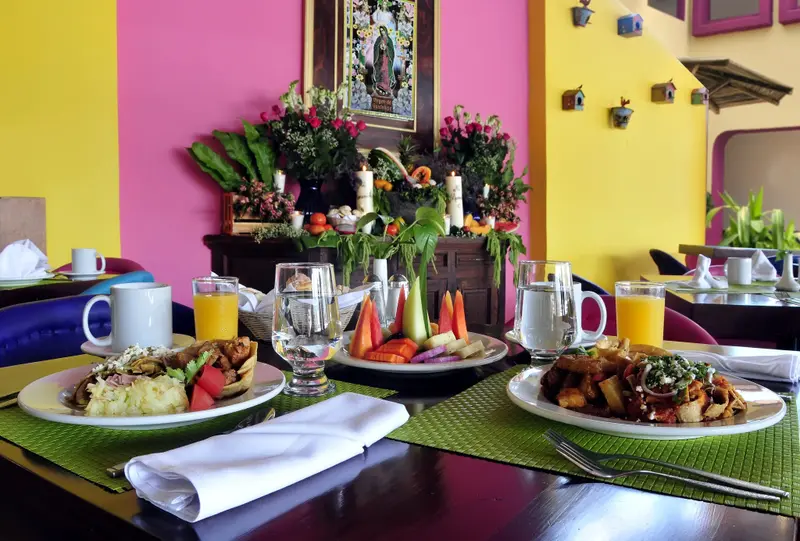 Une table est dressée avec des assiettes de nourriture, des verres et des couverts.