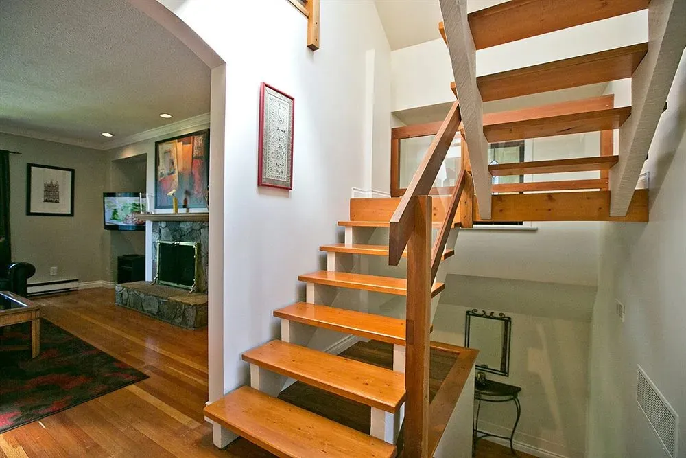 Un escalier en bois clair mène à l'étage supérieur d'une maison.