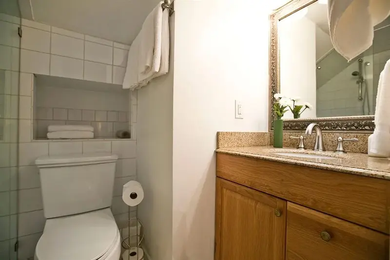 Une salle de bain lumineuse avec douche, lavabo et toilettes.