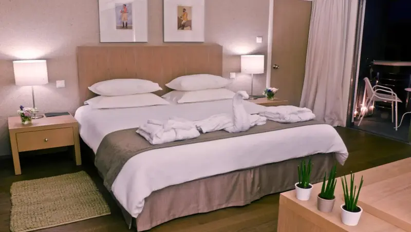 Une chambre lumineuse avec un grand lit décoré de serviettes en forme de cygnes.