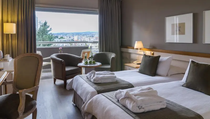 Une chambre d'hôtel lumineuse avec deux lits et un coin salon.